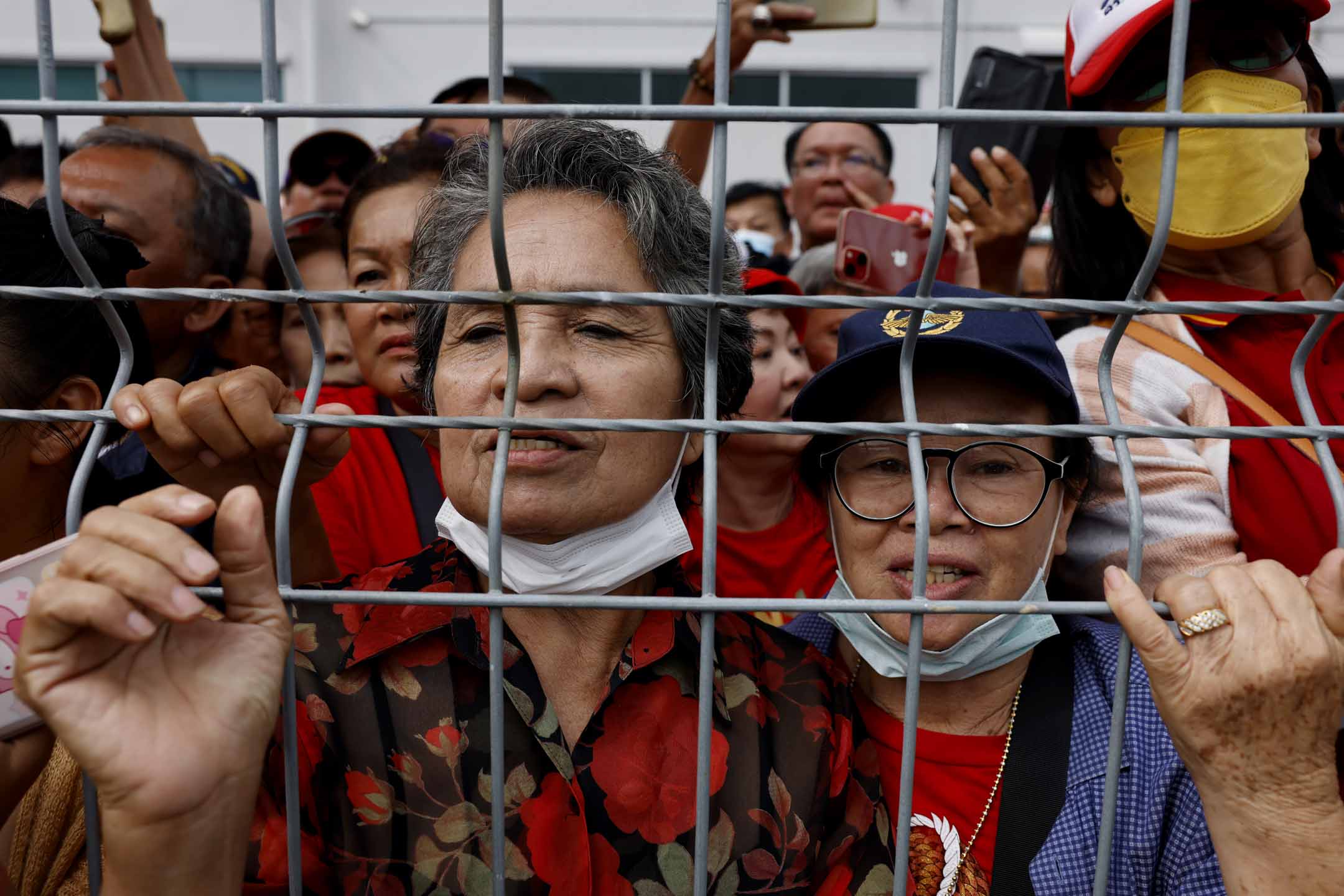 2023年8月22日，他信的支持者聚集在泰國曼谷廊曼國際機場外，聚集在柵欄後面，等待到來。攝：Lauren DeCicca/Getty Images
