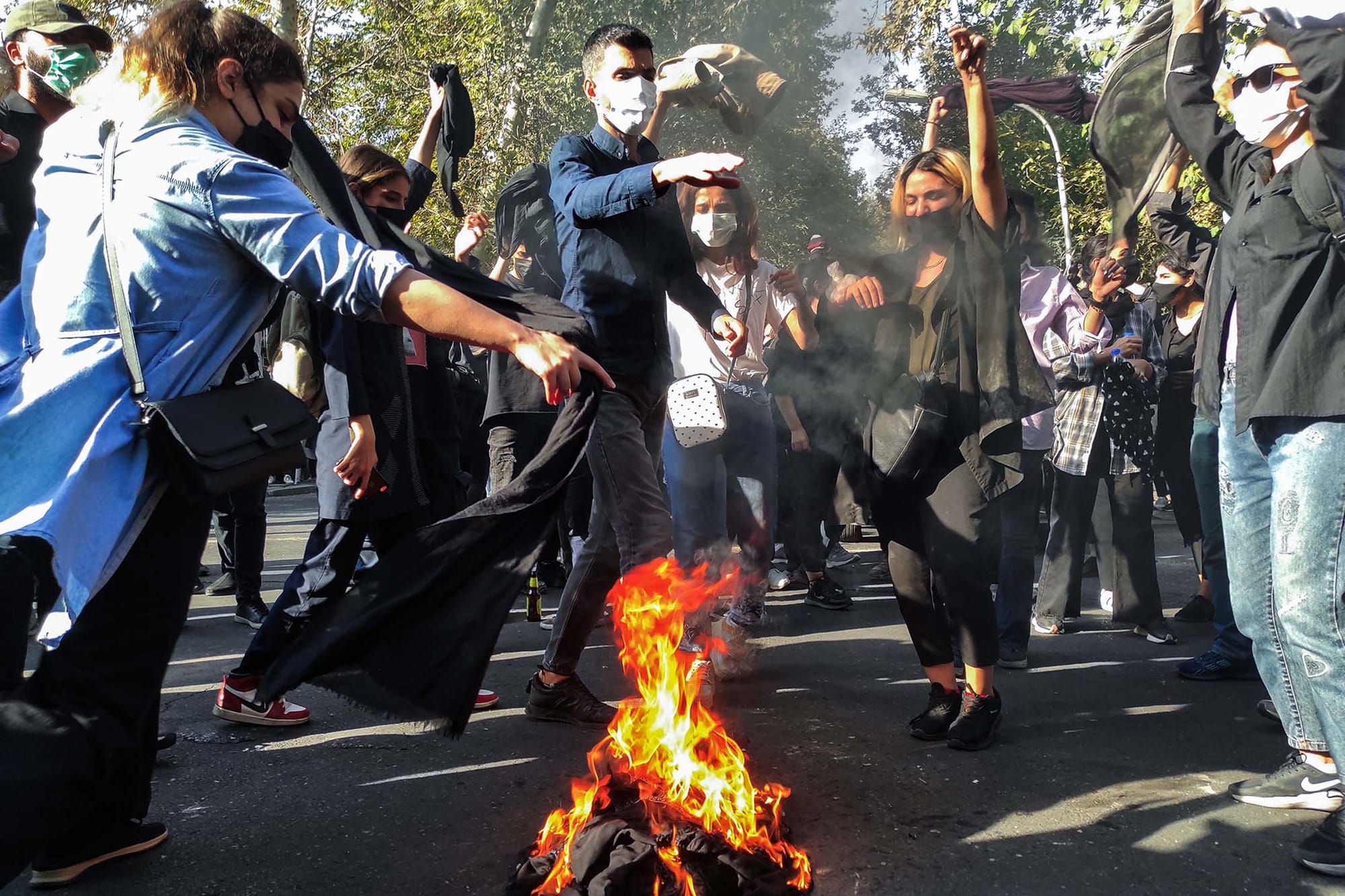 2022年10月1日，伊朗德黑蘭，伊朗抗議者在街道遊行時點燃圍巾。圖：Getty Images