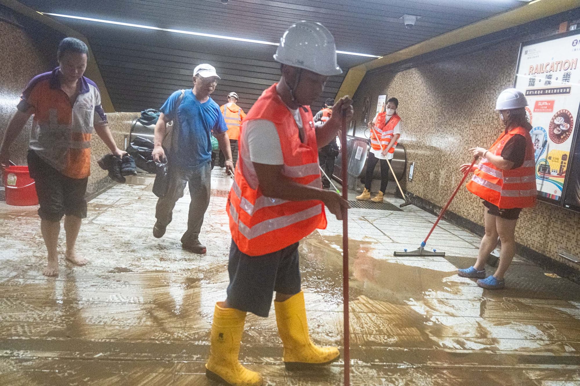2023年9月8日,大水退去后,黄大仙港铁职员在出口清理污泥。摄:Ryan Lai/端传媒
