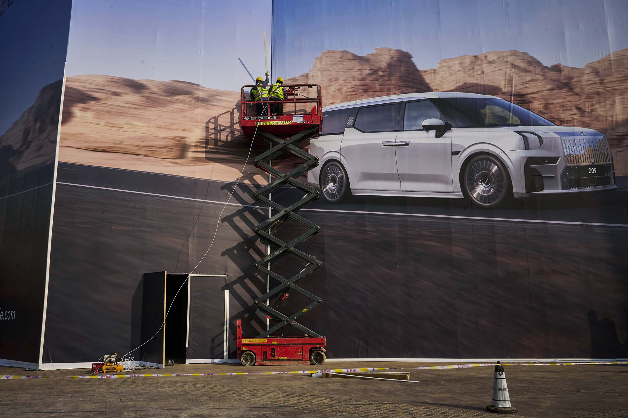 2023年3月31日,北京,工人们为中国电动车制造商安装一块大型广告牌。摄:Kevin Frayer/Getty Images