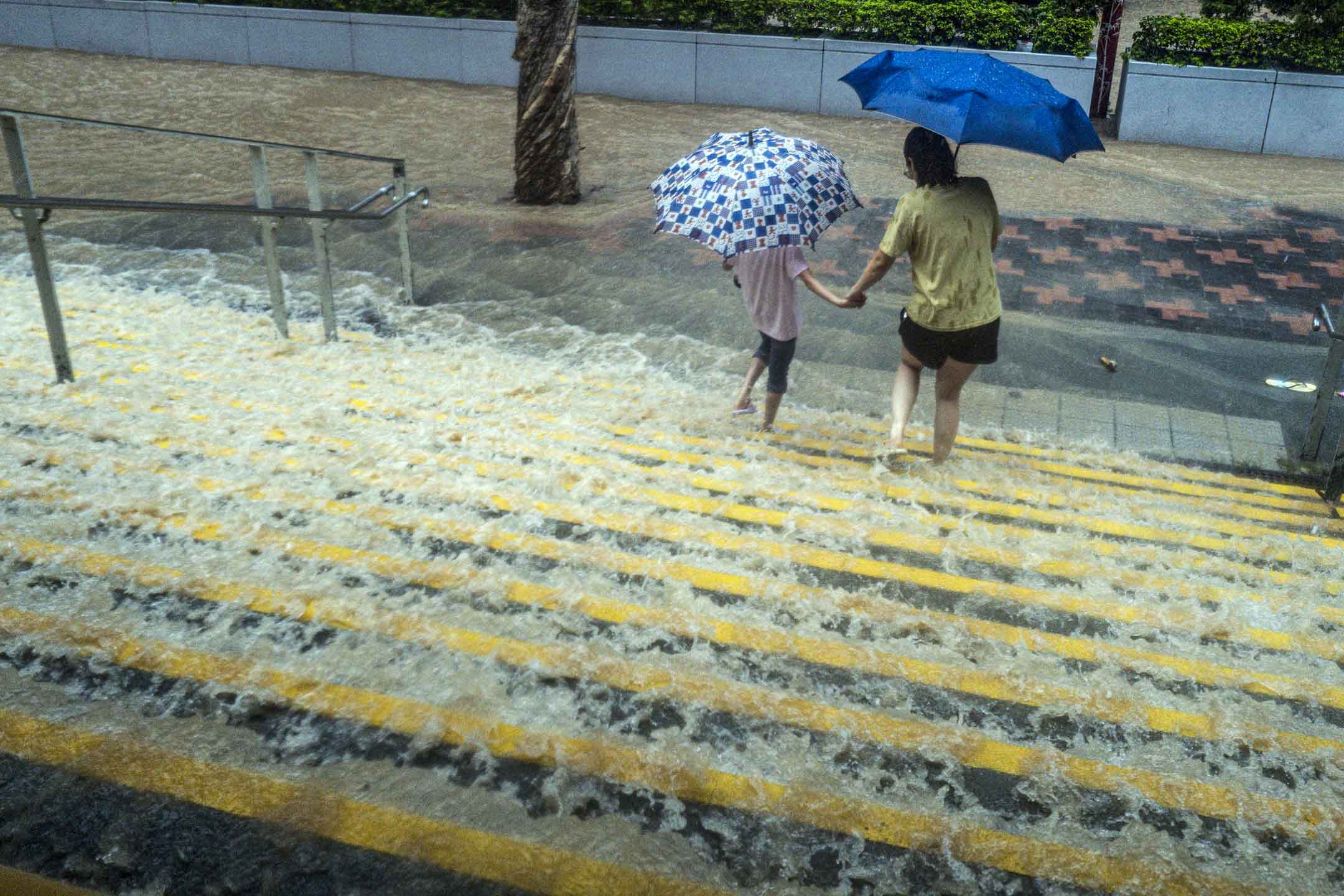 2023年9月8日，暴雨大来的洪水冲过地铁站，市民在水中前行。摄：Lam Yik/Bloomberg via Getty Images