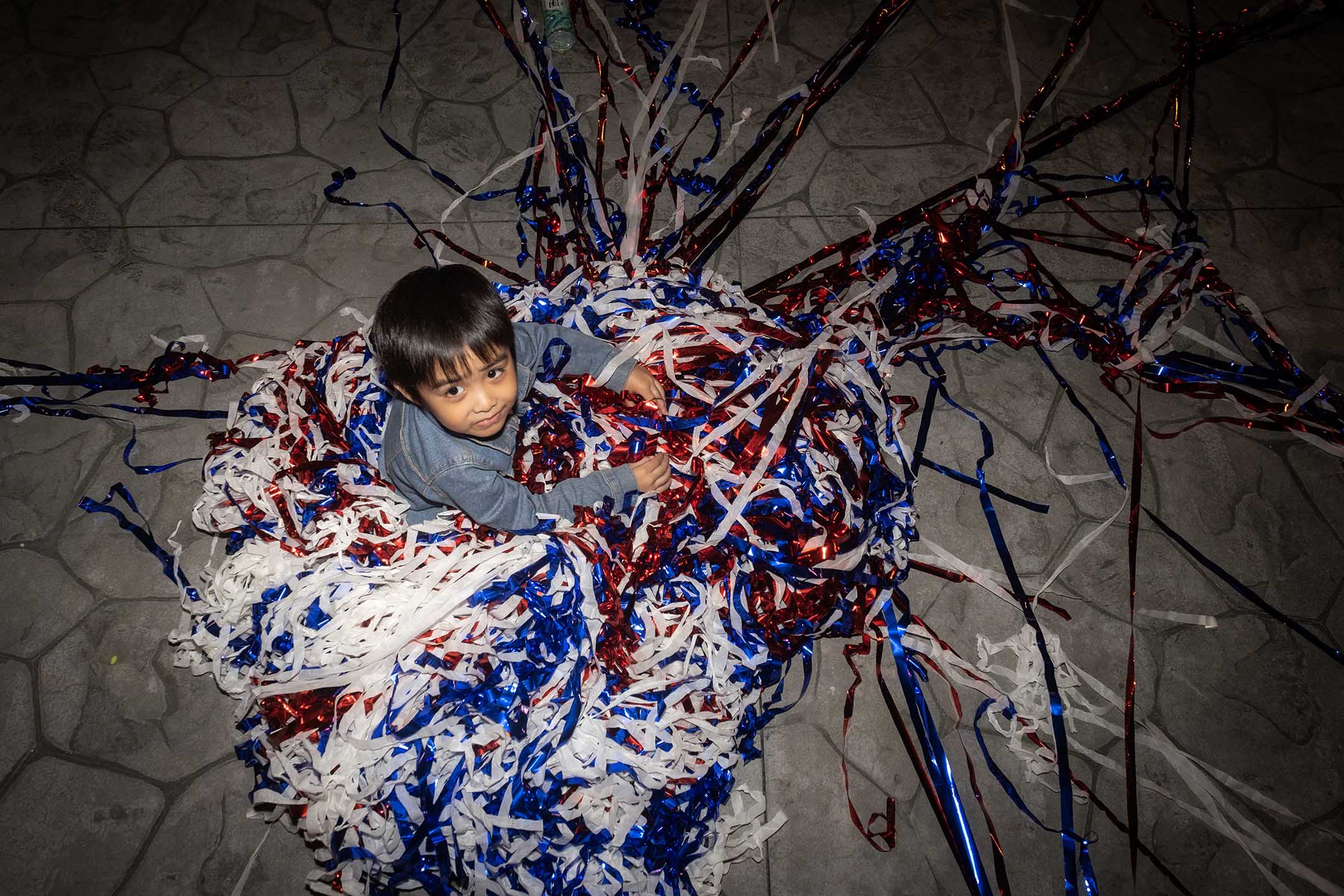 2023年10月24日，新北市，国民党的造势大会过后，小孩在彩带堆中玩耍。摄：陈焯煇/端传媒