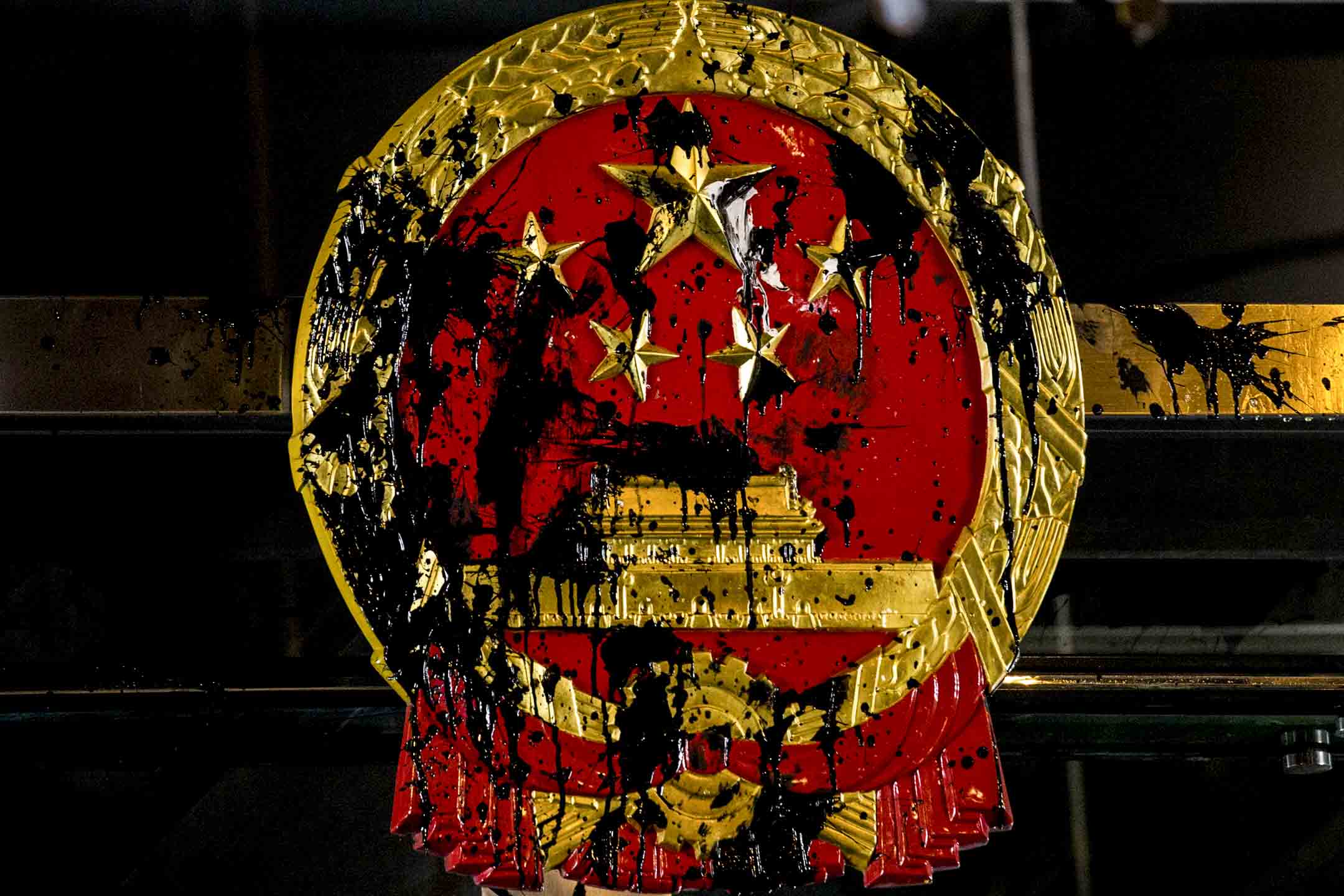 2019年7月21日，示威者到西環的中聯辦集結，門外的中國國徽被漆彈染黑。攝：林振東/端傳媒