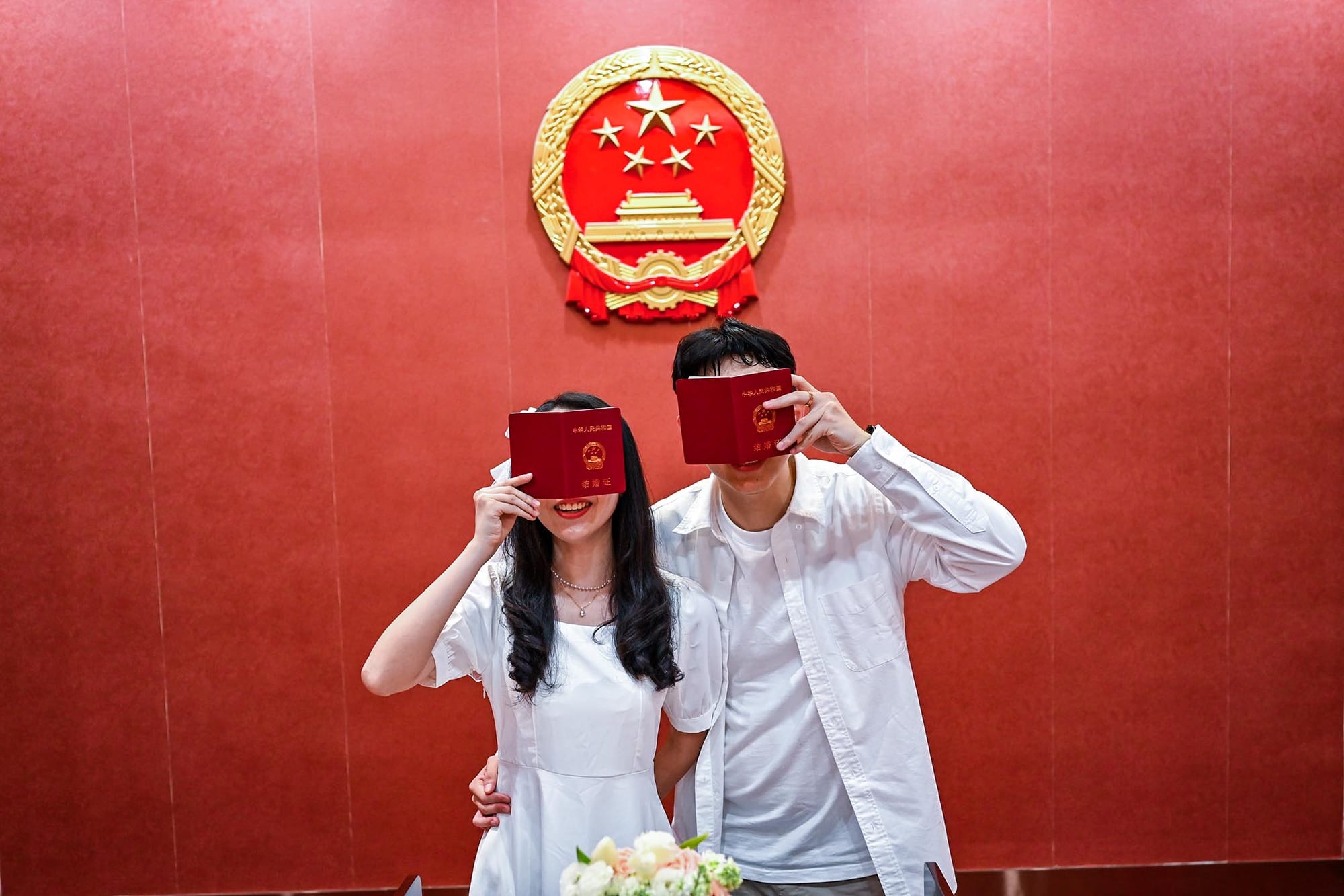 2023年5月20日，一对新婚夫妇在中国福建省泉州婚姻登记中心拿著结婚证书摆拍。摄：Xie Mingfei/VCG via Getty Images