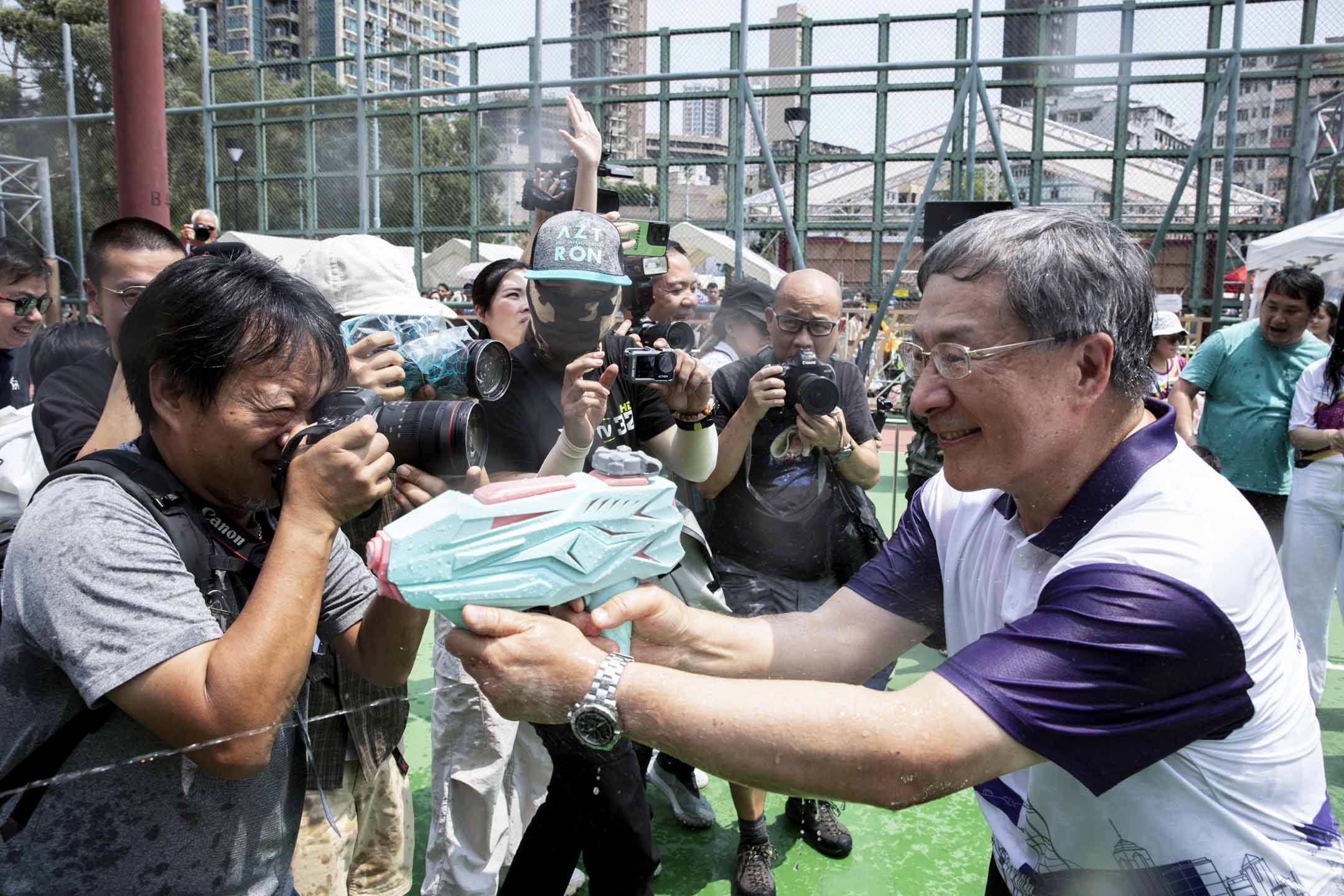 2024年4月13日,政務司副司長卓永興到籃球場與市民互相射水,期間有小朋友以水槍「追擊」卓永興。攝:林振東/端傳媒