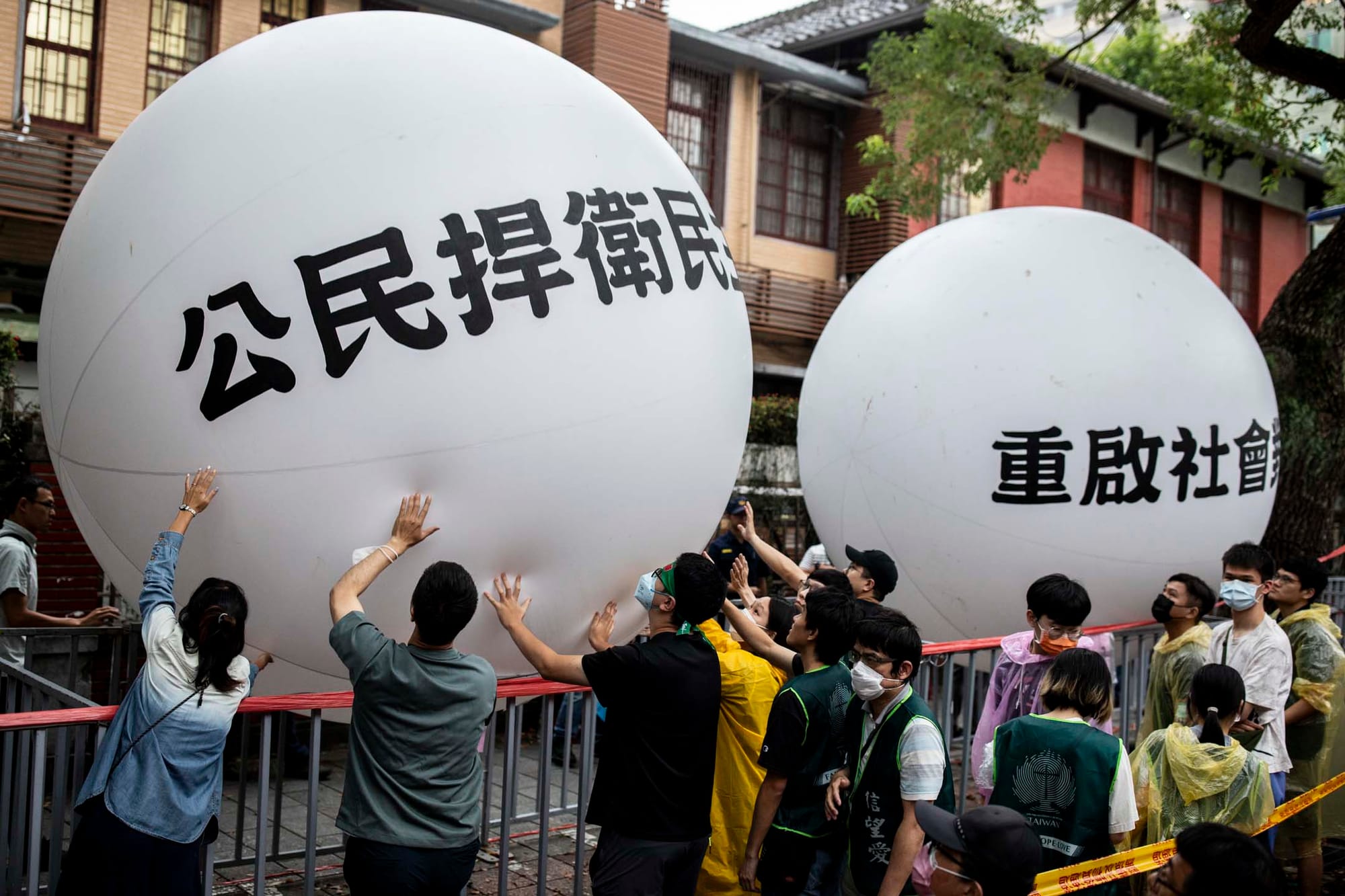 2024年5月28日,台北,立法院进行国会改革法案审议,立法院外有民众集会,抗议民众把写著“公民捍卫民主”、“重启社会对话”的大型气球,接力传递到立法院前,表达这次行动诉求。摄:林振东/端传媒