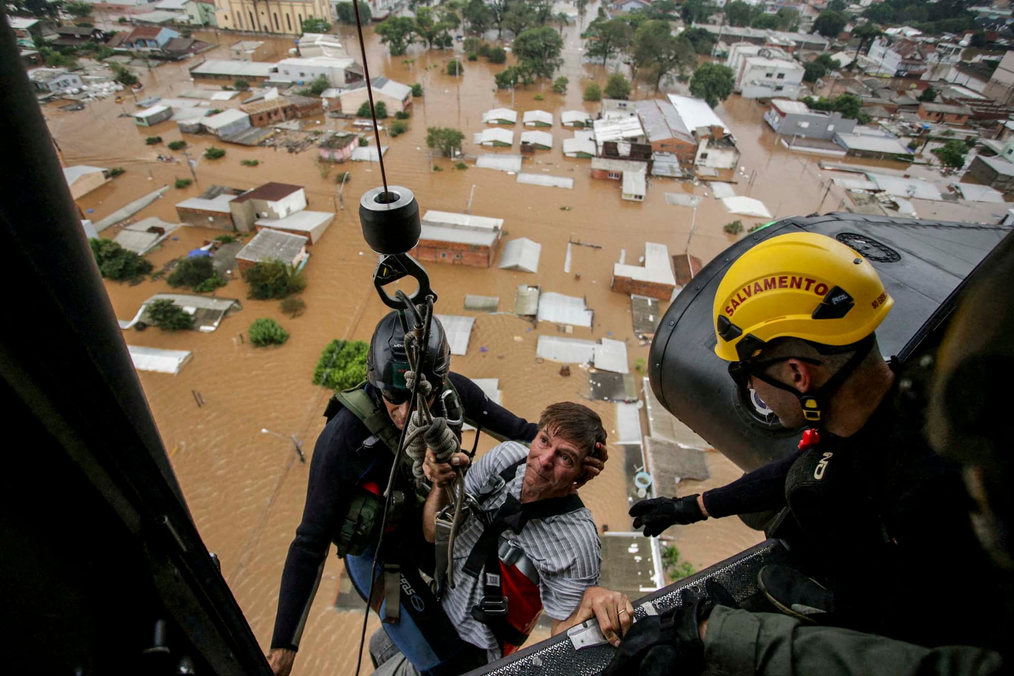 2024年5月4日,巴西南里奧格蘭德州卡諾阿斯發生洪水後,一名男子被軍事消防員救出。攝:Renan Mattos/Reuters/達志影像