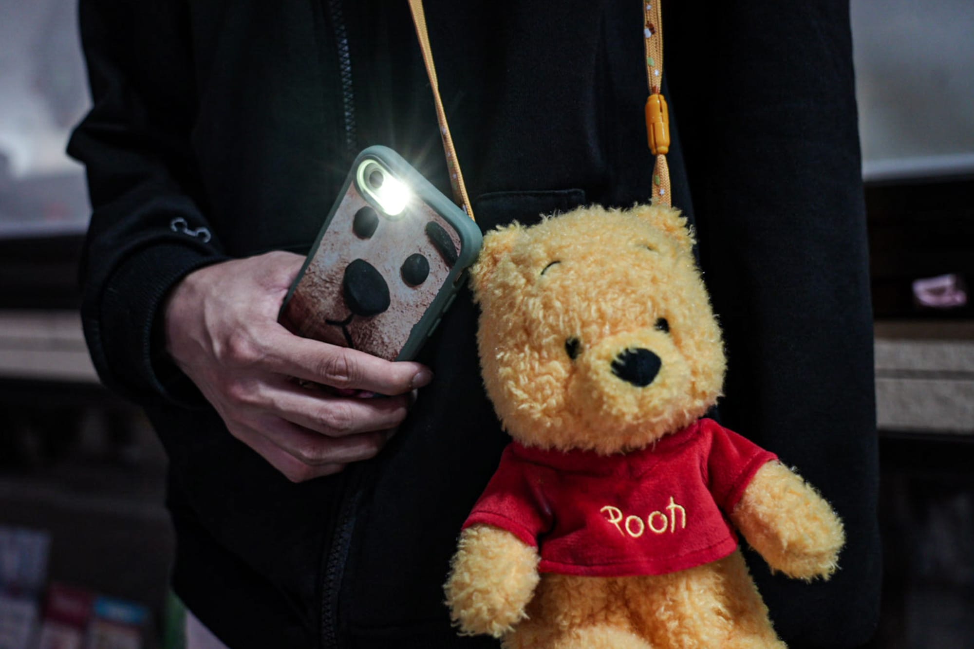 2024年6月4日，一名女士在銅鑼灣街角，手提電話亮著電筒模式，並拿著小熊維尼玩偶。攝：Ryan Lai/端傳媒