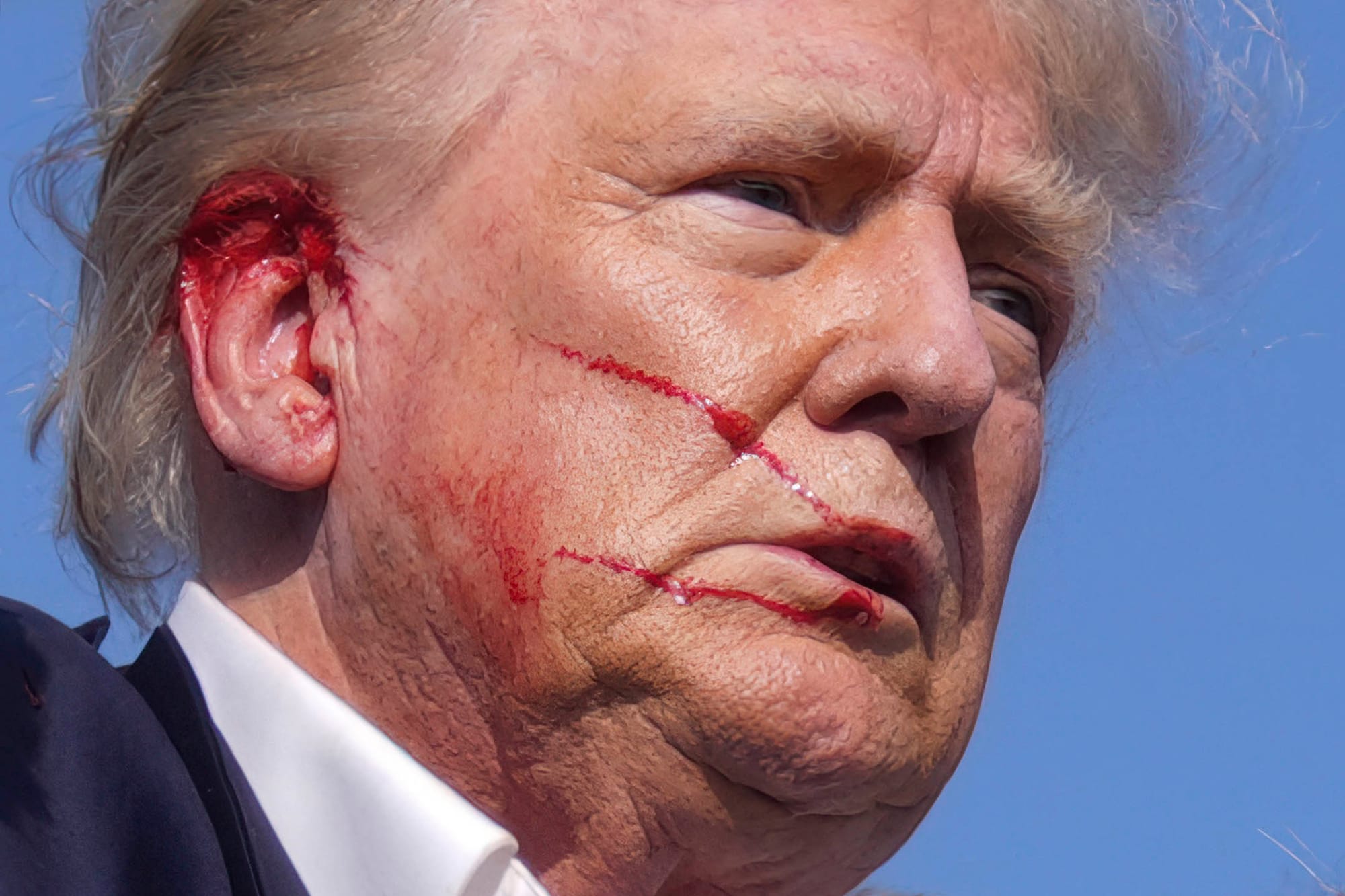 2024年7月13日,賓夕法尼亞州巴特勒,共和黨總統候選人、前總統特朗普在競選集會發表演講時,現場傳出疑似槍聲,被美國特勤局特工包圍離開,期間特朗普臉上有血。攝:Evan Vucci/AP/達志影像