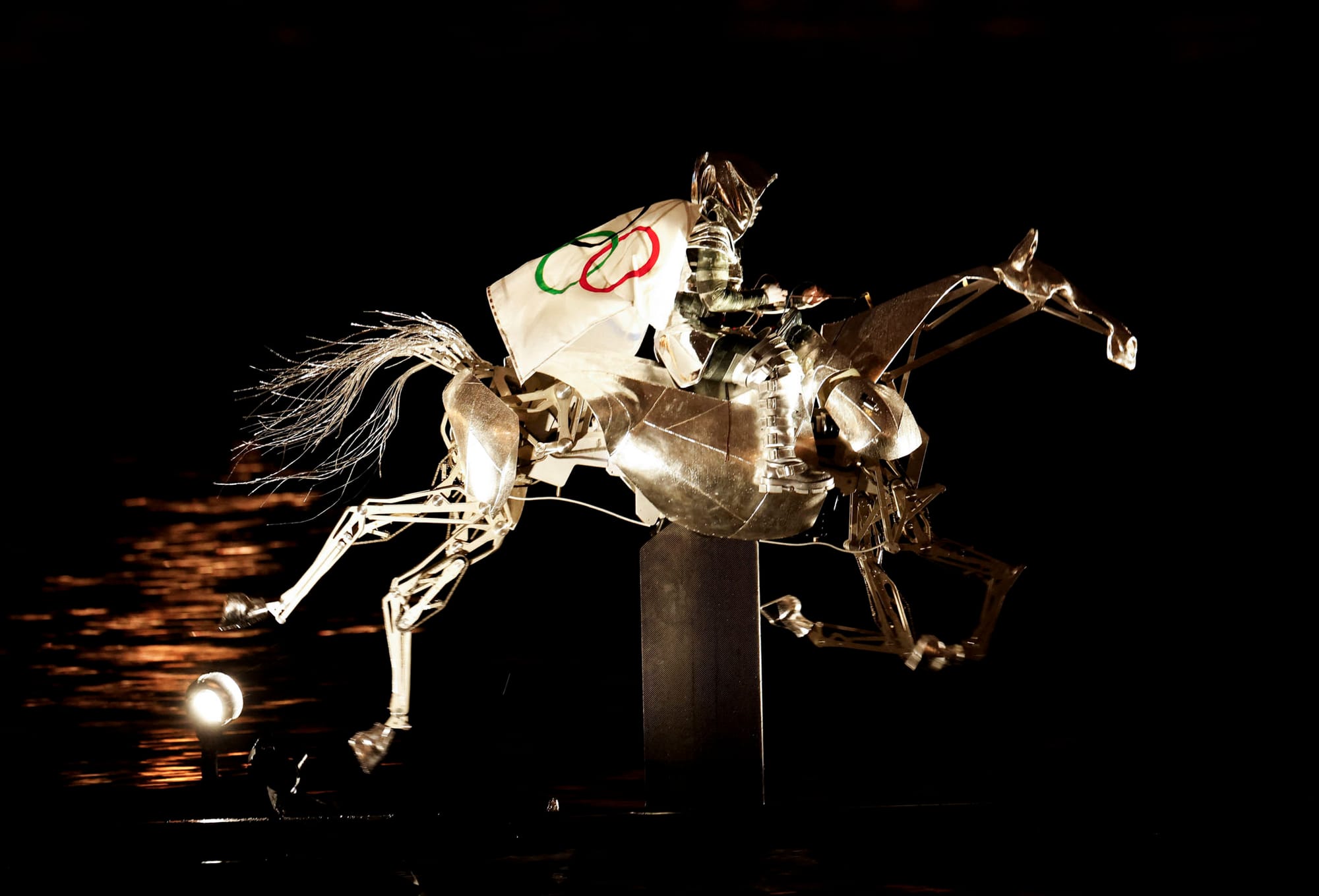 2024年7月26日，身著银色盔甲、披上奥运会旗的女骑手穿梭过塞纳河。摄：Adnan Abidi/Reuters/达志影像