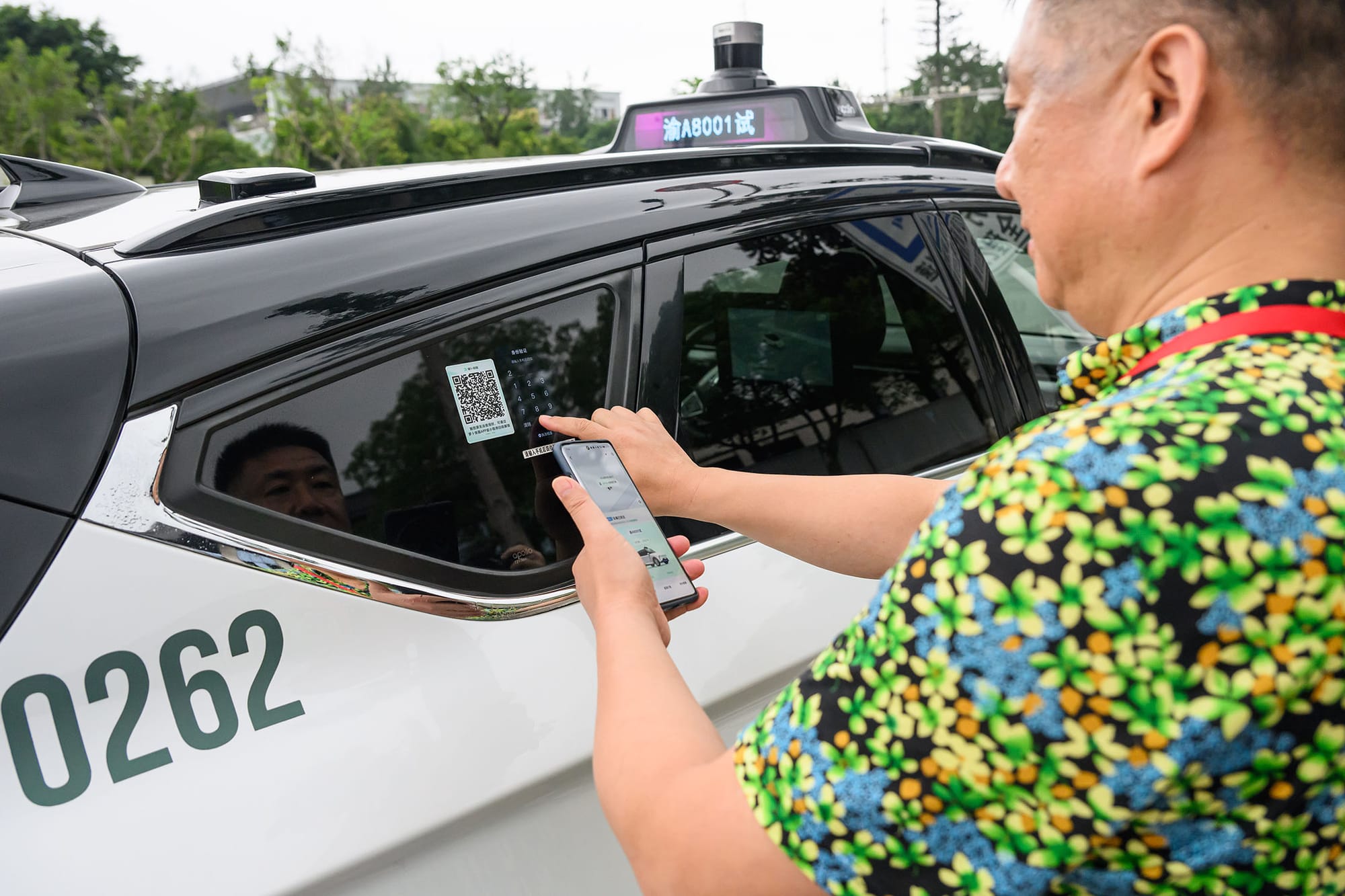 2024年7月10日,中国重庆,乘客扫描二维码乘坐无人自动驾驶出租车平台“萝卜快跑”。摄:He Penglei/China News Service/VCG via Getty Images