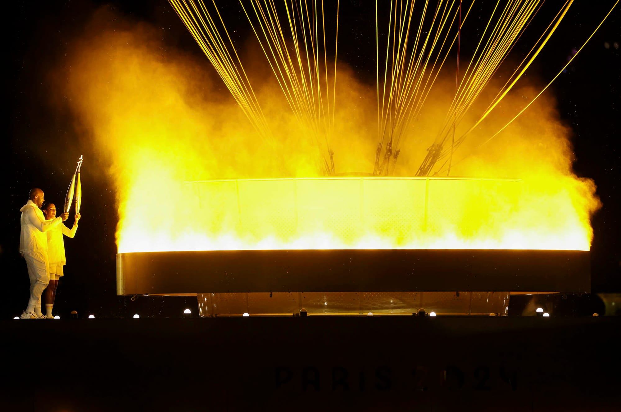 2024年7月26日，前短跑运动员Marie-José Pérec和柔道运动员Teddy Riner 以圣火在杜乐丽花园点燃一个巨大的热气球。摄：Carl Recine/Getty Images