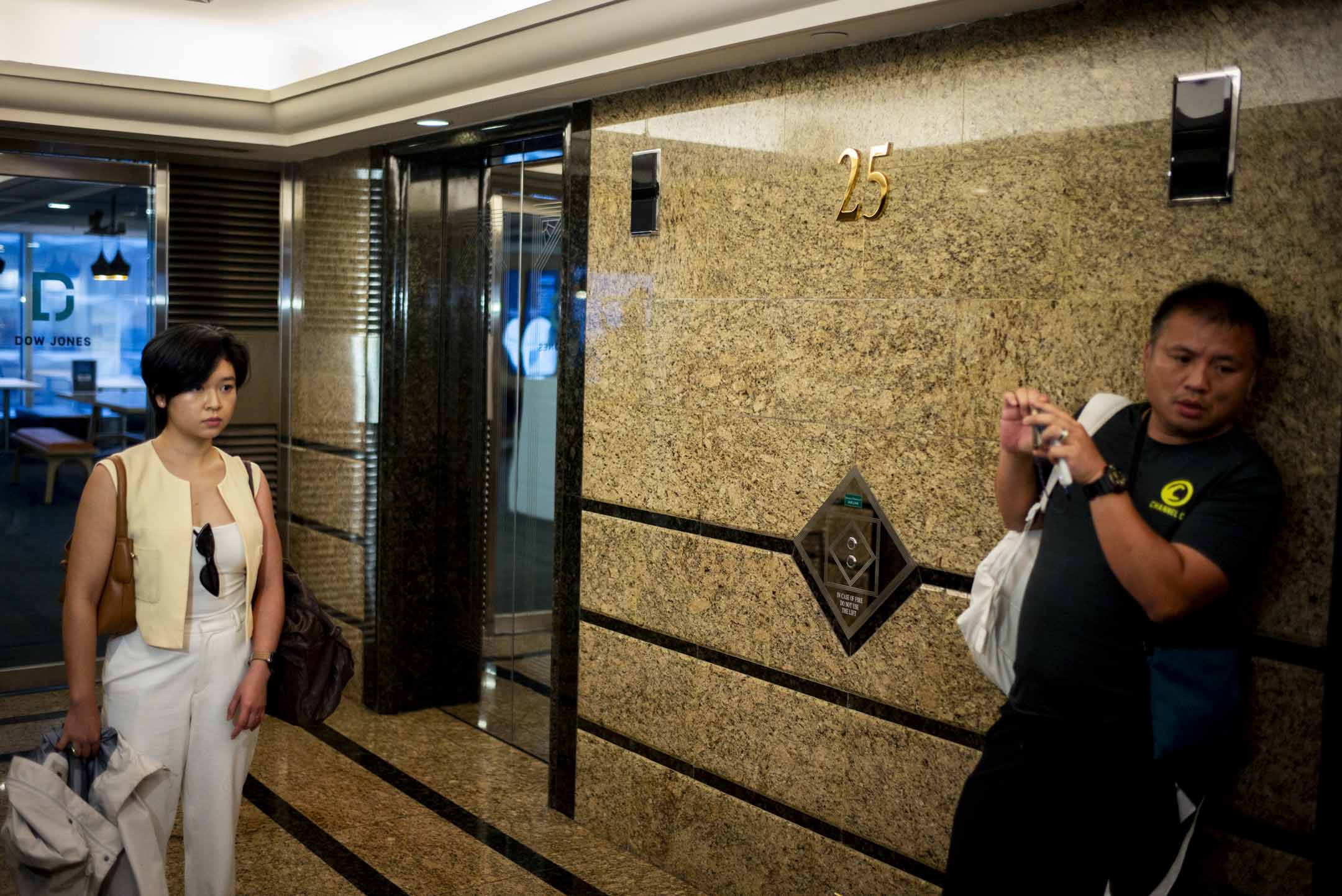 2024年7月17日,香港記者協會主席鄭嘉如遭《華爾街日報》辭退後,離開中環廣場的辦公室,被大批傳媒追訪,期間記協前主席陳朗昇亦在現場採訪。攝:林振東/端傳媒