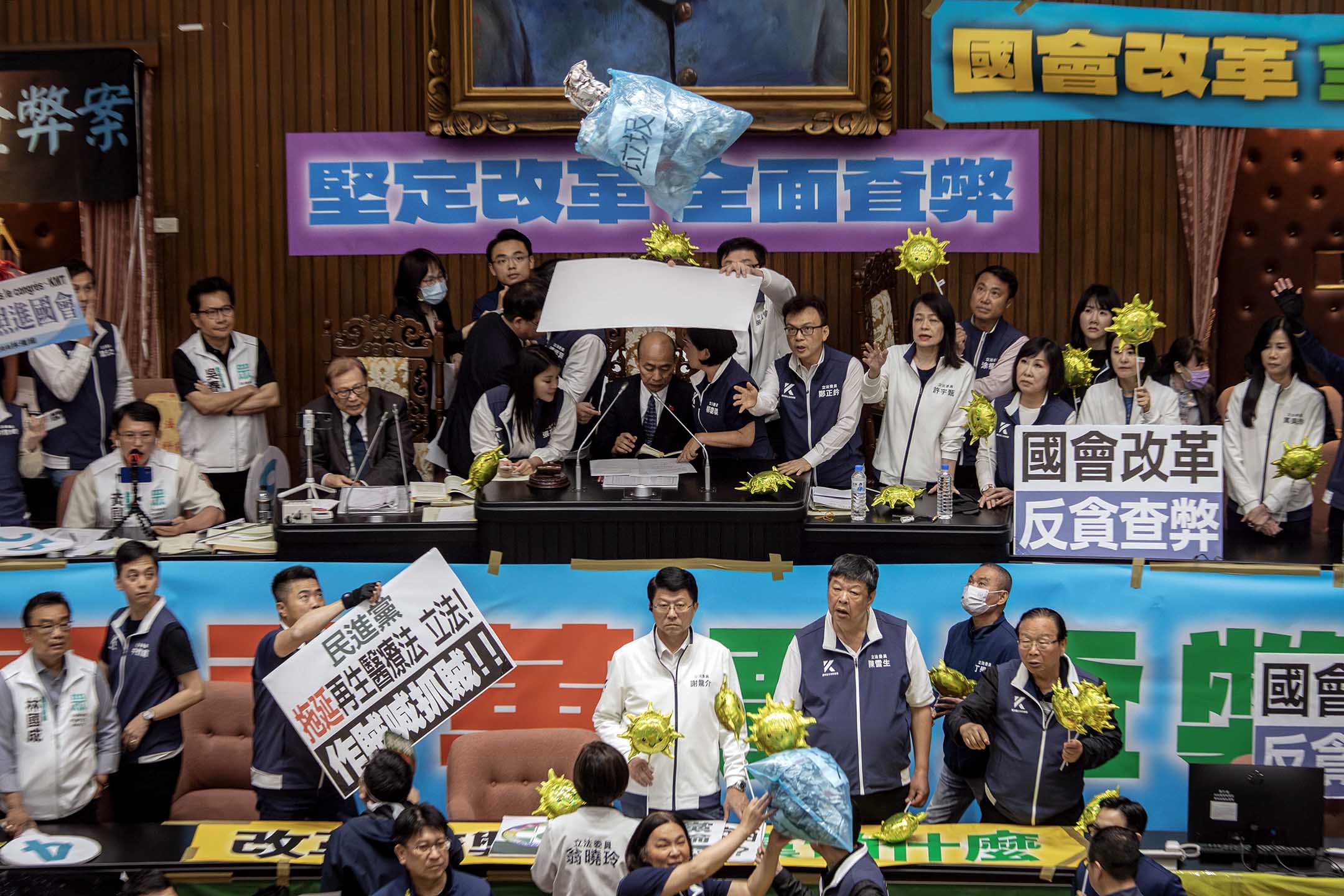 2024年5月28日,台北,立法院进行国会改革法案审议,立法院内民进党立委向主席台掉垃圾,国民党立委用看板阻挡保护立法院长韩国瑜。摄:陈焯煇/端传媒