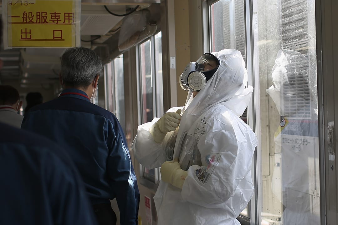 工作人员在进入核污染区前,在一座抗震建筑内换上保护衣物。摄:Christopher Furlong/GETTY