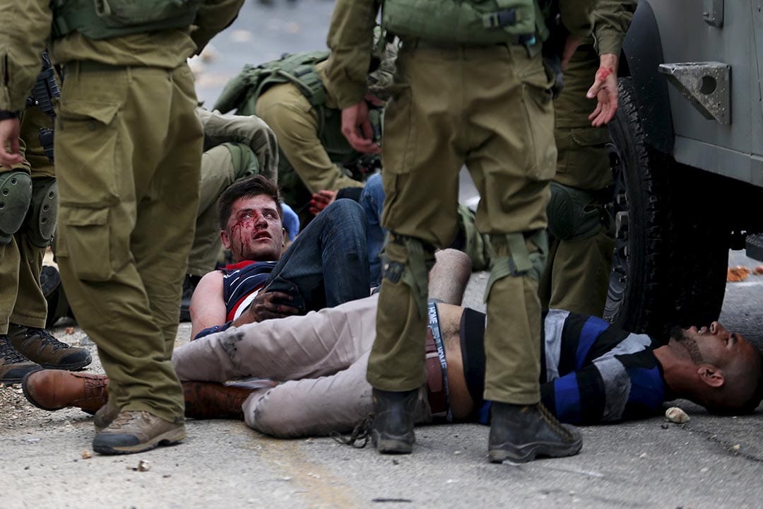 2015年10月7日，约旦河西岸，以色列军人扣留一名在冲突中受伤的巴勒斯坦男子。摄:Mohamad Torokman/REUTERS