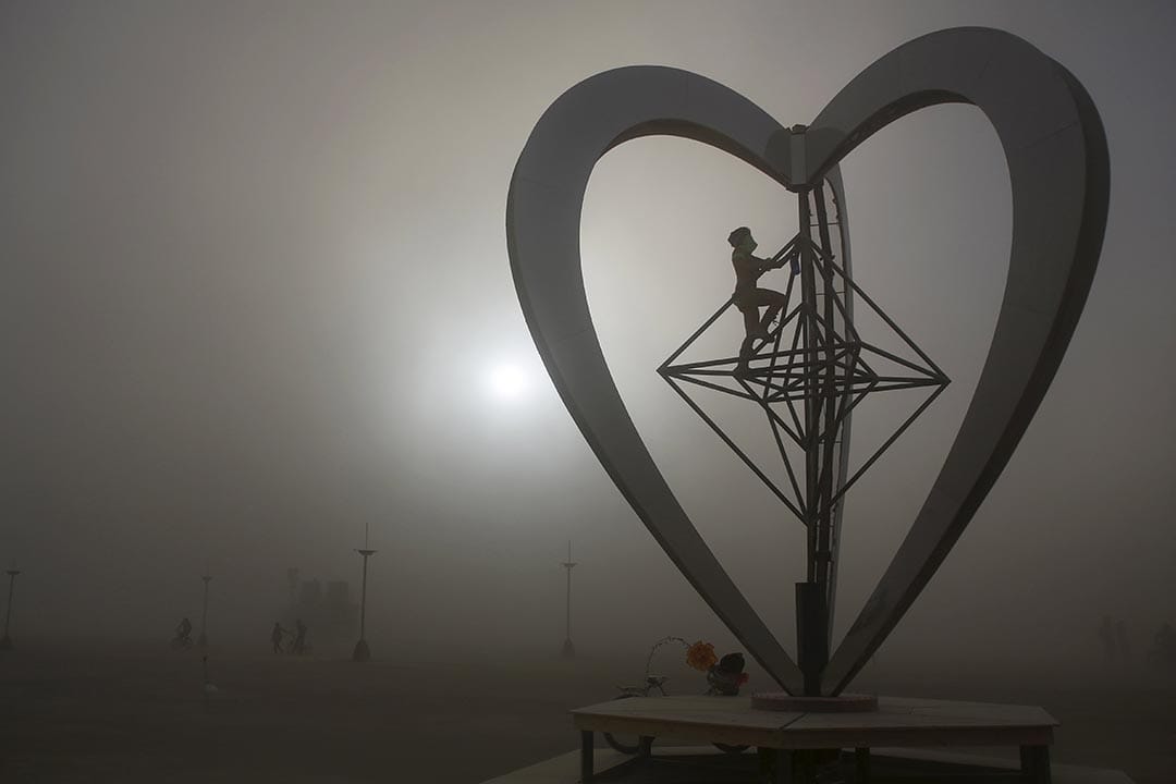 沙漠刮起沙塵暴，仍有參加者冒險攀上裝置藝術品METAHEART。攝：Jim Urquhart/Reuters