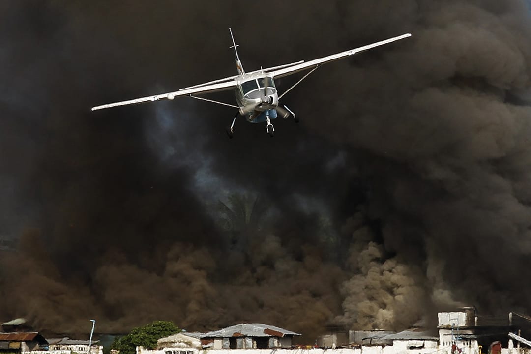 Kalay市的油站冒出大量黑烟,飞机接走部分灾民。摄: Soe Zeya Tun /REUTERS