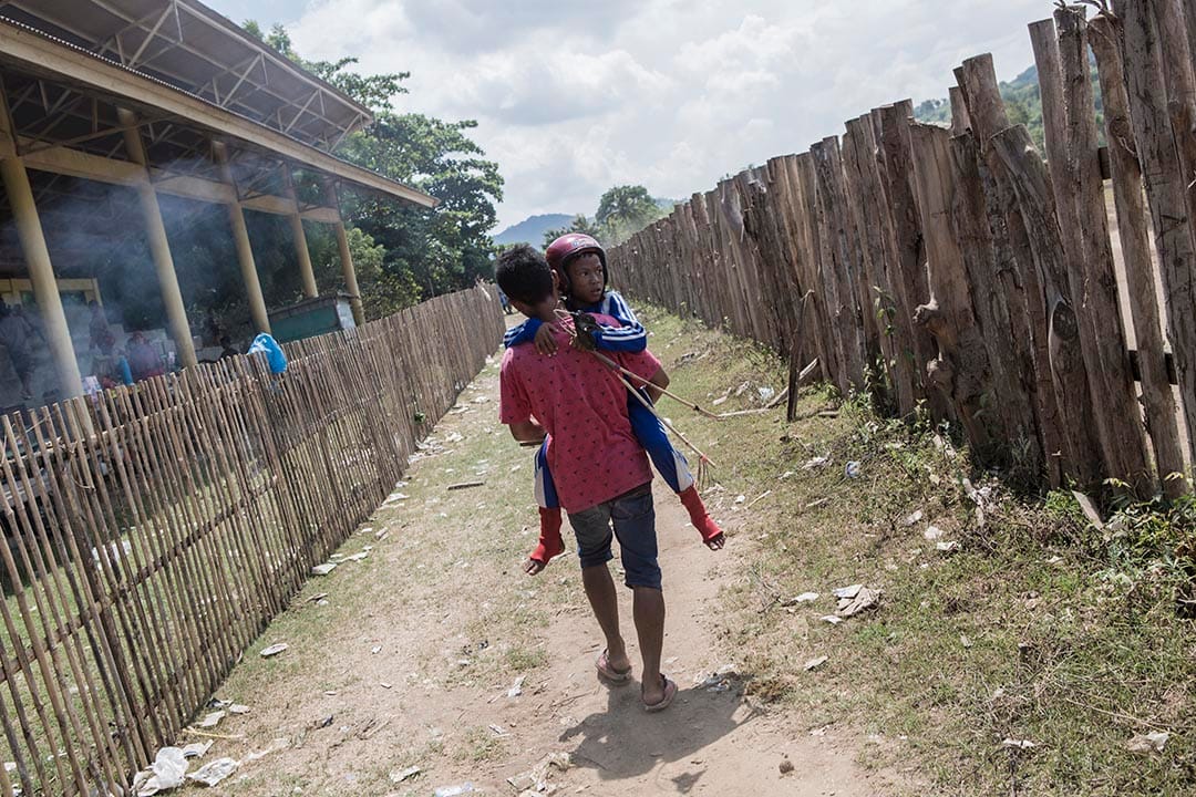 年僅九歲的小騎師在比賽中墮馬弄傷腳部,唯有靠哥哥抱他往起跑線參與下一場比賽。攝:Putu Sayoga