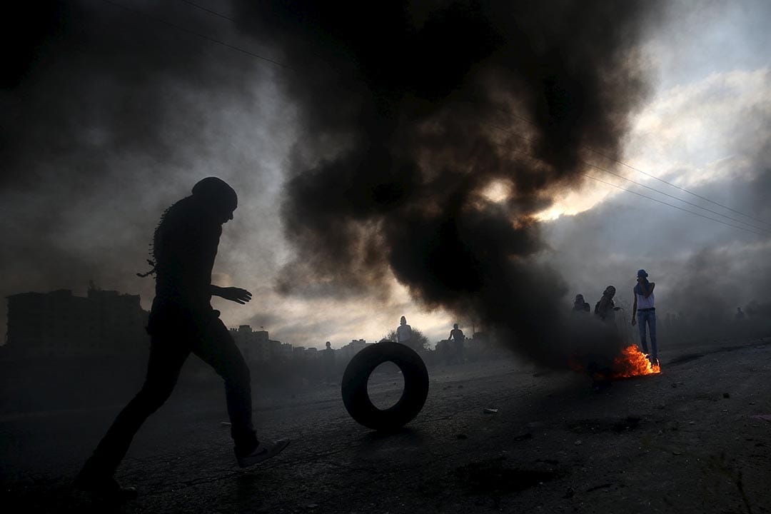 2015年10月5日约旦河西岸， 一名巴勒斯坦示威者滚动轮胎作为障碍物。摄:Mohamad Torokman/REUTERS