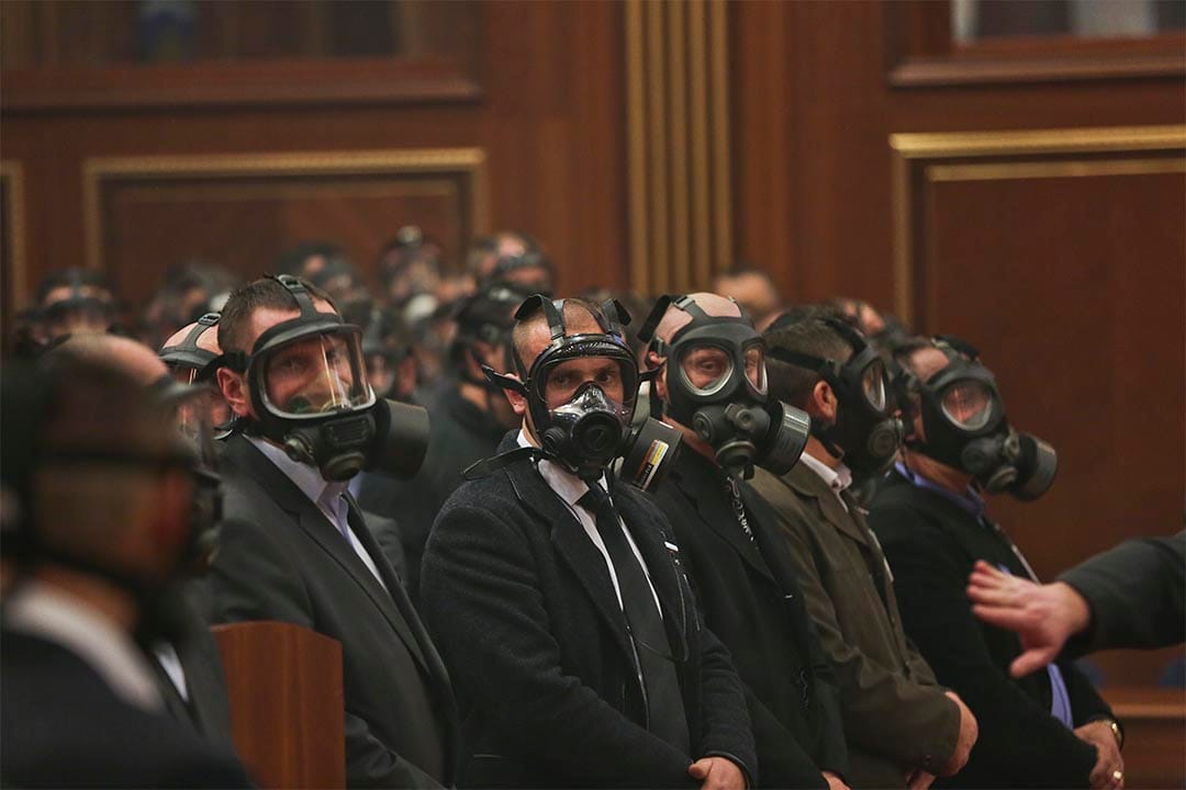科索沃反对派议员投放催泪弹，干扰议会会议，警察戴着防毒面具站岗。摄：Visar Kryeziu/AP