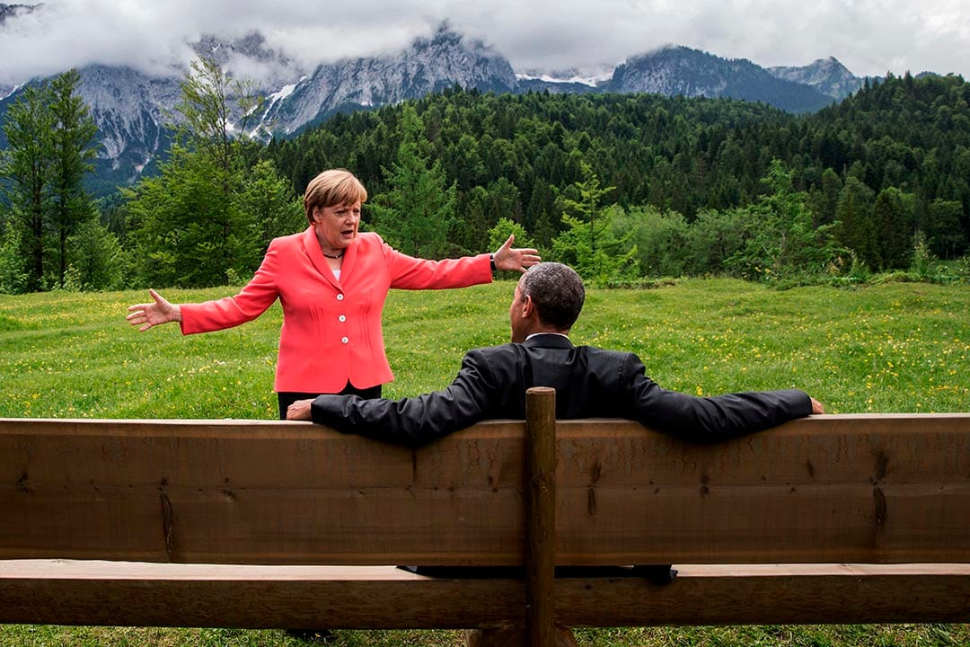 2015年6月8日,G7七國集團峰會期間，德國總理默克爾與坐在長椅上的美國總統奧巴馬傾談。攝：Michaek Kappeler/Pool Photo via AP