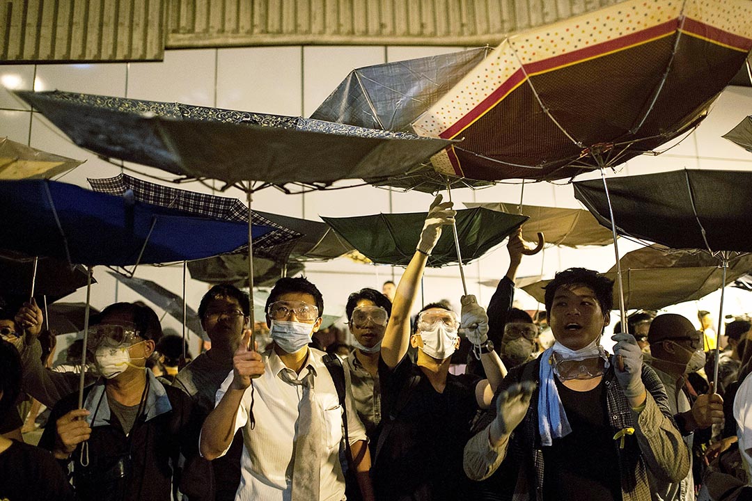 雨伞运动期间，示威者用雨伞挡住胡椒喷雾。图为2014年10月14日，示威者占领龙和道。