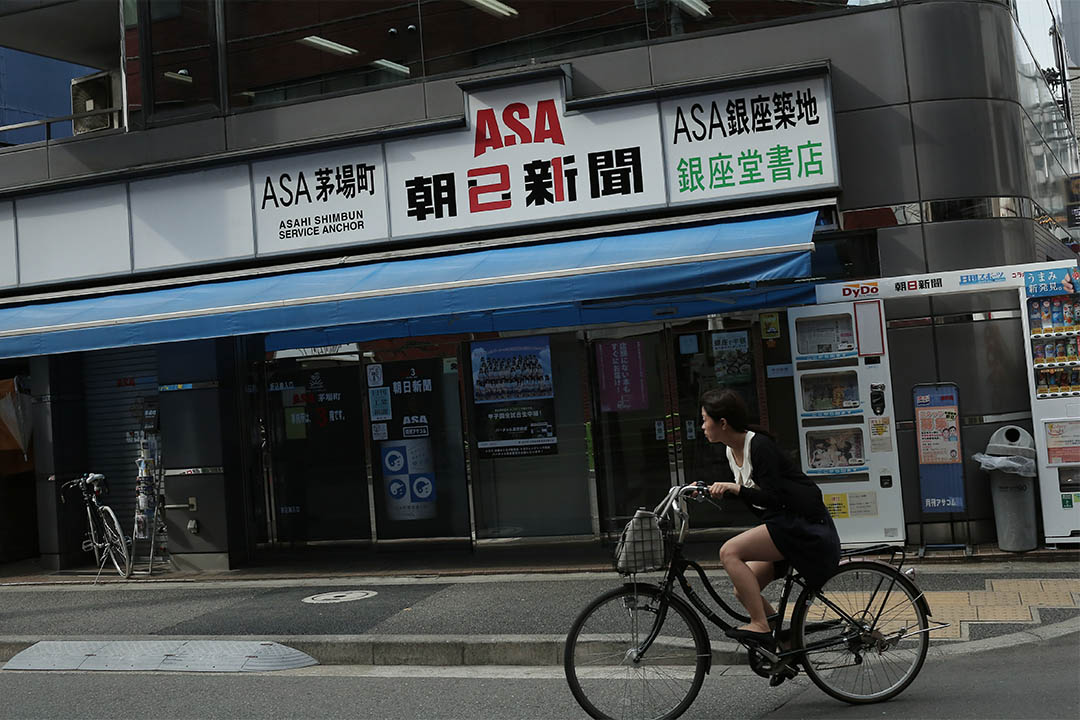 2016年8月3日，日本東京，一個女士騎着單車駛過朝日新聞茅場町辦公室。