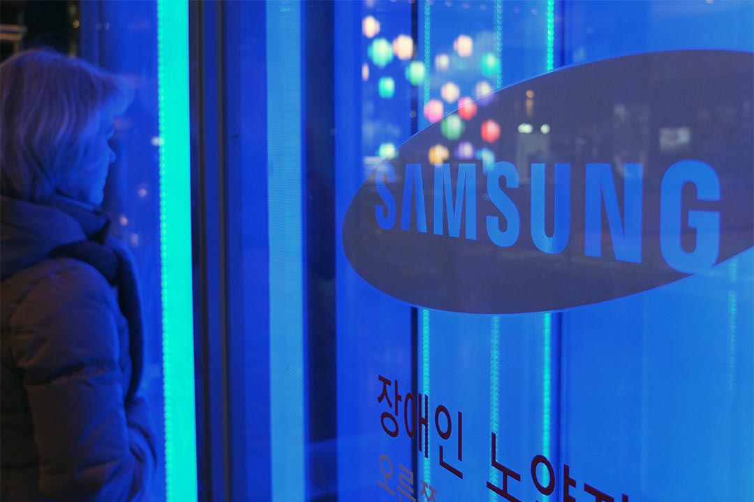 一位女士站在Samsung总部大门旁。