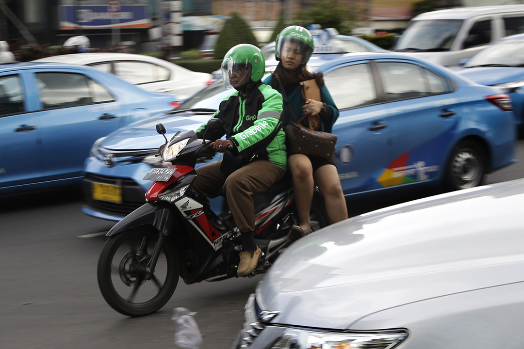 2016年4月29日，印尼雅加达，一名GrabBike的司机载着乘客在街头穿行。