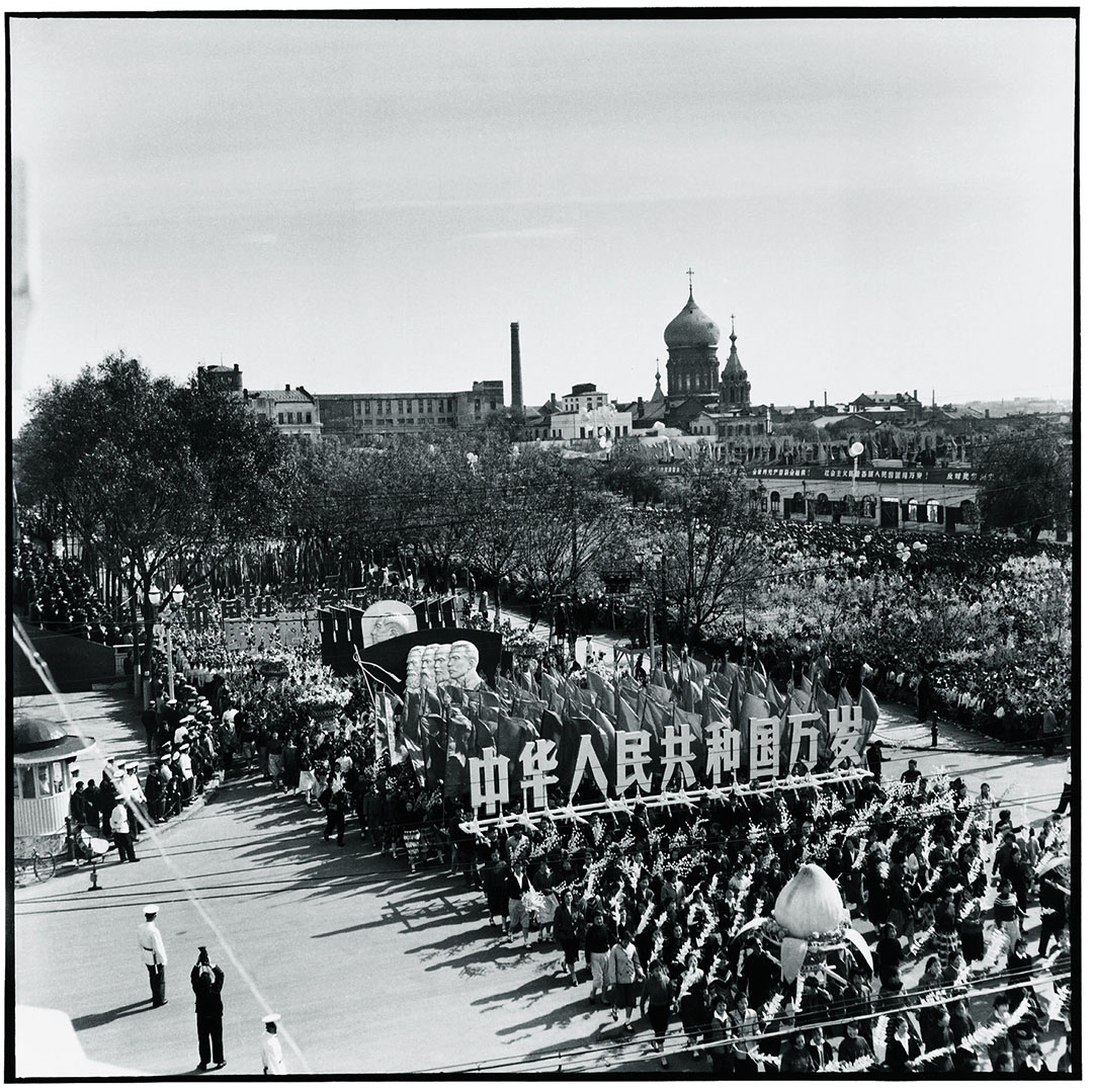 1963年10月1日哈尔滨，国庆阅兵期游行人士高举写着「中国人民共和国万岁」大字的木板，其后是毛泽东、马克思、恩格斯、列宁、史达林的头像。旁边是圣索菲亚大教堂。