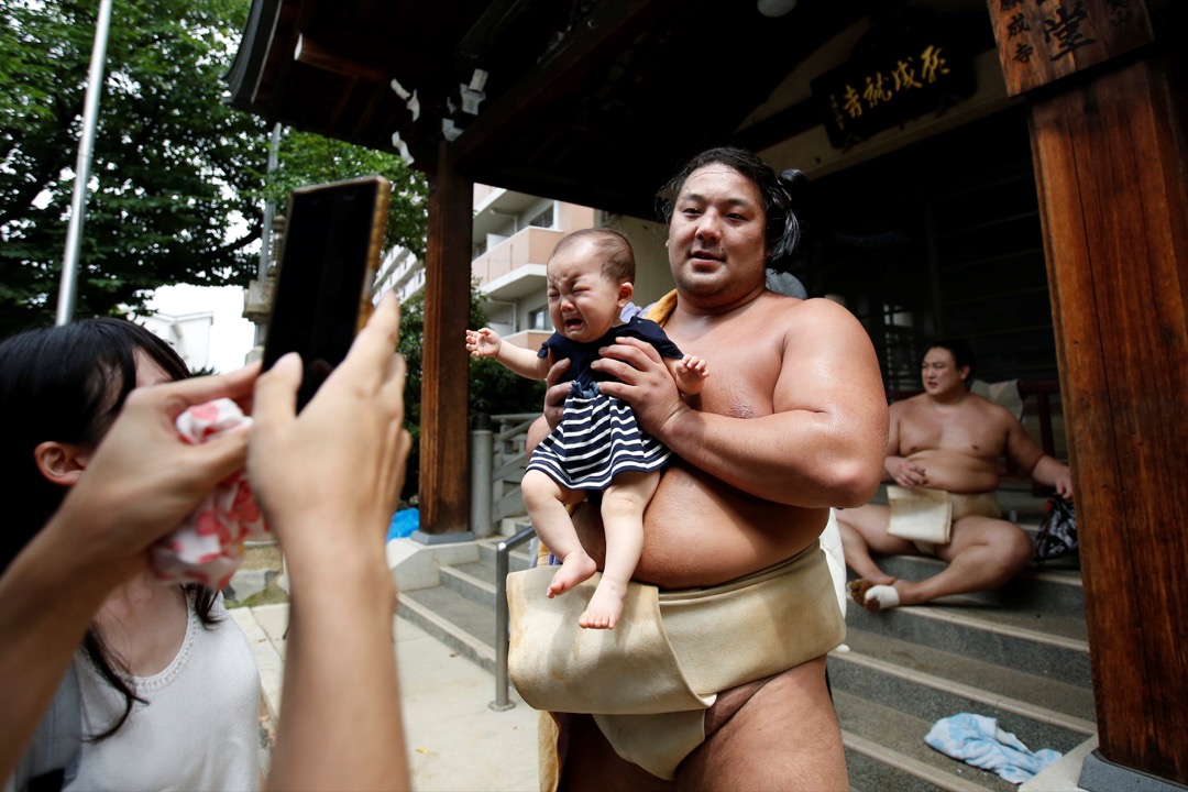 相扑手 Kyokutaisei 在 Ganjoji Yakushido 寺庙训练完毕后与婴儿合照。