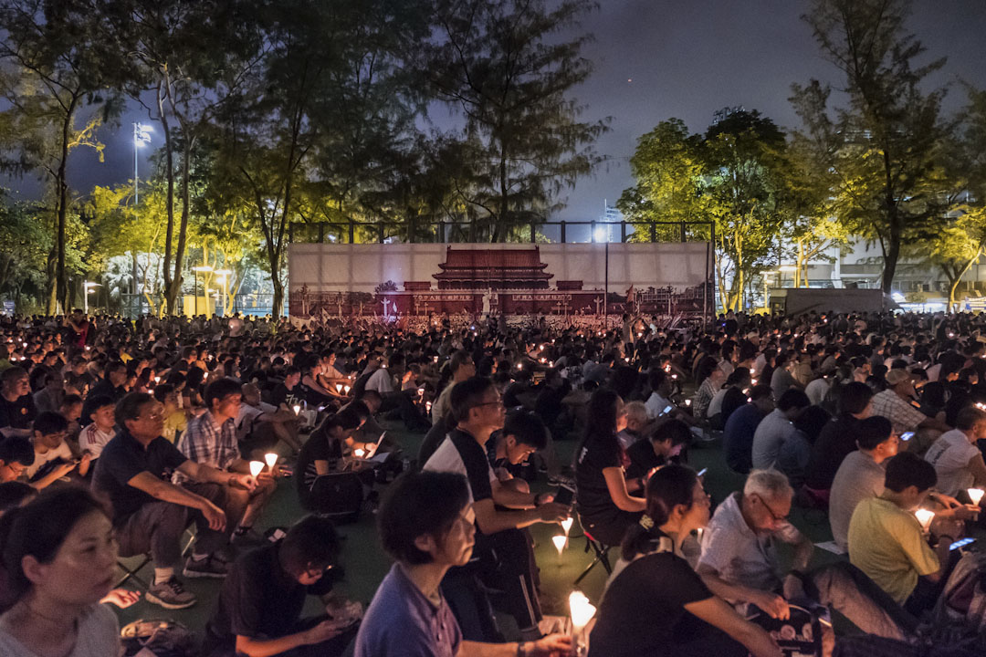 2017年6月4日，香港維園舉行六四晚會。參與者在天安門廣場的大橫幅旁，手持燭台，悼念天安門事件中的死難者。