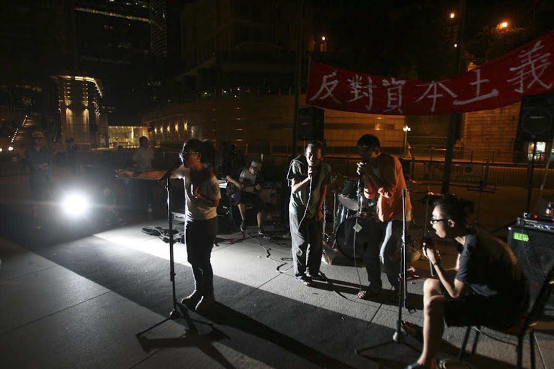 2011年的秋天，香港一批社運青年響應佔領華爾街運動，佔領中環的匯豐總行地面廣場，撐起帳蓬，組織物資進場，準備長期留守；橫額上有剛勁筆跡寫著「打倒資本主義」。