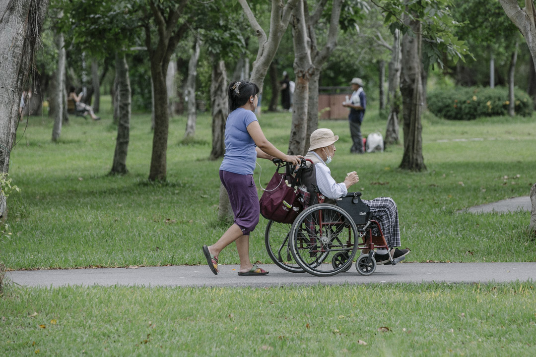 台湾子女对“照顾老人”的想像，恐怕还是“送养老院”这样的图像居多，但多半都会面对“不孝”的骂名，许多子女不堪指责、也不忍心与父母分离，便选择让外籍劳工来家照顾父母。图为台北大安森林公园，外籍看护照顾长者。 