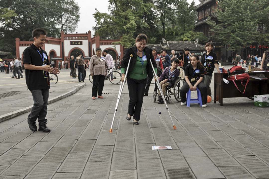 残障人士最终都要与家人在社区里过活，香港复康会希望“可以改变社区去帮助残障人士，而不是教残障人士怎样上两级楼梯”。图为香港复康会在都江堰举办活动。