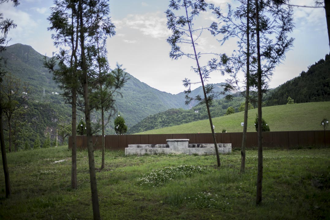 “就是这片小山坡，当年的北川中学和孩子们，就埋在下面，这前面的绿草坪，就是以前的操场。”北川县城一名老人。