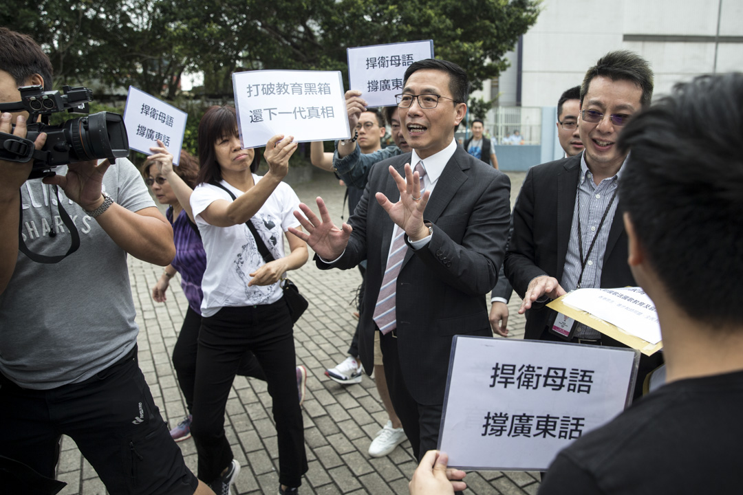 2018年5月4日，教育局局長楊潤雄到一間中學出席活動前，與香港眾志的秘書長黃之鋒等人對話，並接收請願信。楊潤雄指並無打算改變兩文三語的政策。攝：端傳媒