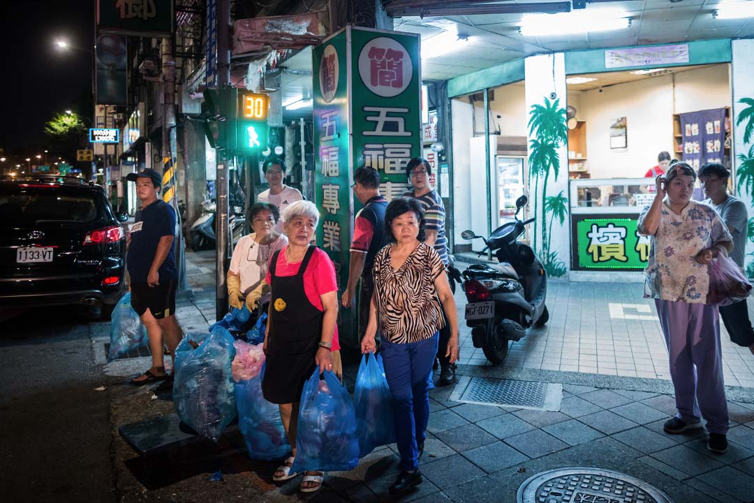 在台灣，垃圾清潔費有兩種收費方式：都會區如雙北市的隨袋徵收是一種，由垃圾袋大小決定承載垃圾量多寡，也決定了個人製造的垃圾，必須付出相對的代價。圖為台北龍山寺的居民等候垃圾車收垃圾。