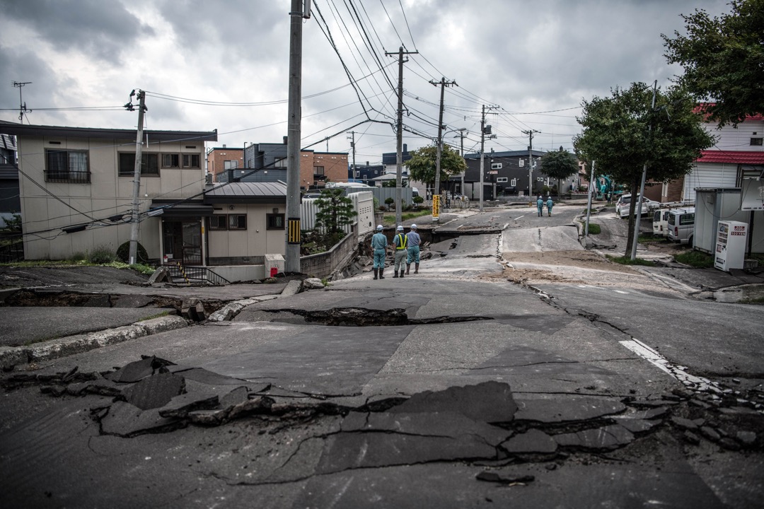 2018年9月7日，日本札幌清田區，道路在地震中嚴重損毀，數名維修人員在場觀察情況。