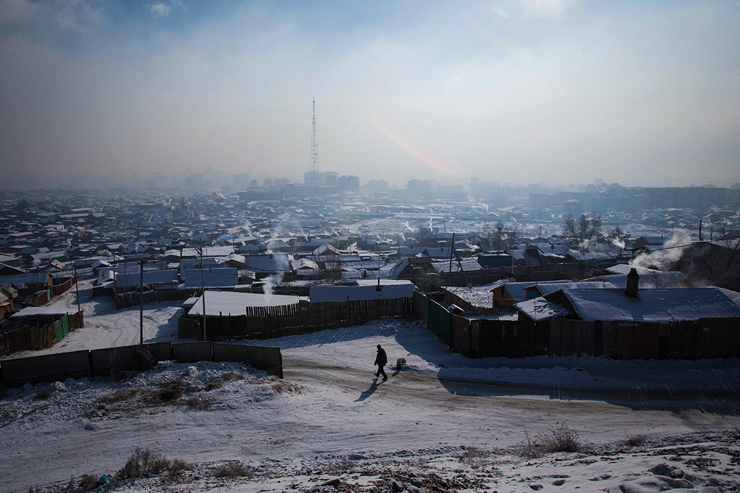 2018年1月21日，在蒙古首都乌兰巴托空气污染严重，一名男子走在冰冷的道路上，烟雾笼罩著城市。