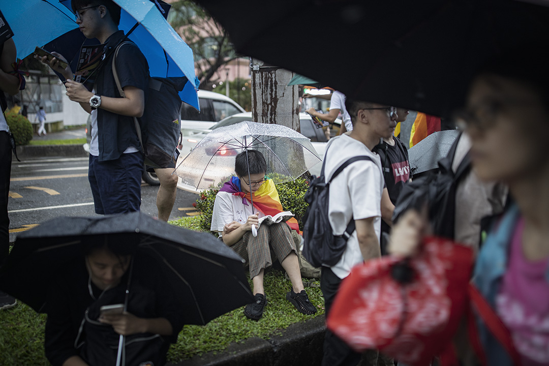 2019年5月17日，台北立法院外挺同团体发起集会，参加者在大雨下举伞等候投票结果，一名支持者在看书。