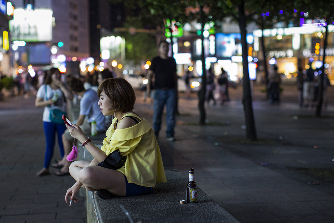 一名女子在台北的街头看手机及抽烟。