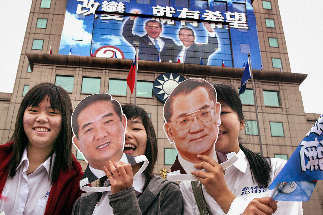 2004年3月19日，女孩在台北国民党总部前举起台湾总统候选人连战和副总统候选人宋楚瑜的面具。 