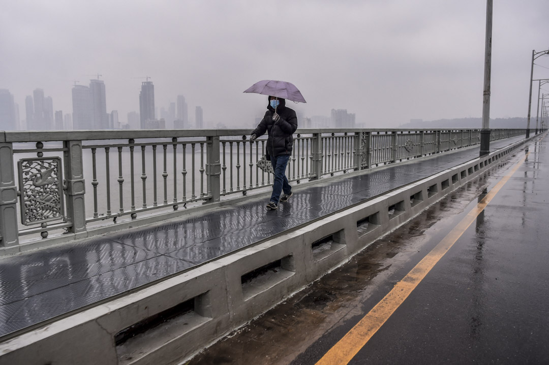 2020年1月25日，一名戴著口罩的男子在武漢的一座橋上行走。