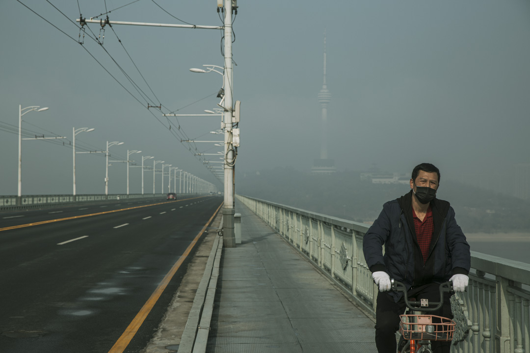 武漢一名戴著口罩的男士騎著單車在武漢長江大橋上。