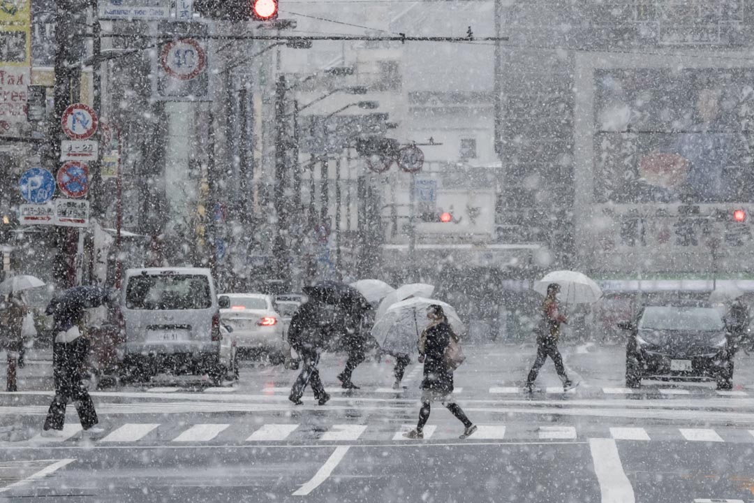 2020年3月29日，日本东京降雪，人们戴着口罩在浅草区过马路。 