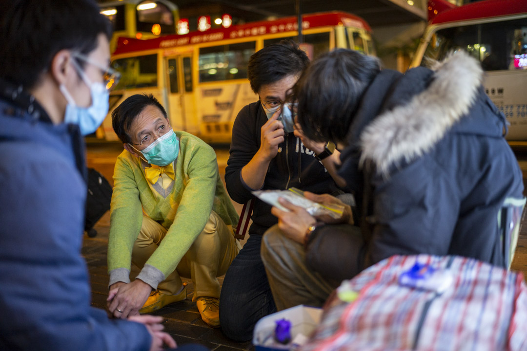 黎青龙跟医学生和社工在湾仔寻找露宿者的身影，逐个跟他们聊天和派口罩。