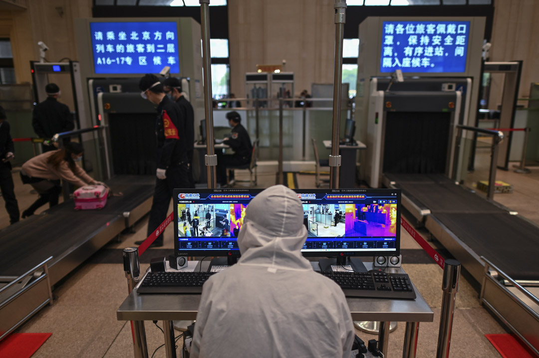 2020年4月8日，武漢漢口火車站一名穿著防護服的工人負責測量乘客的體溫。