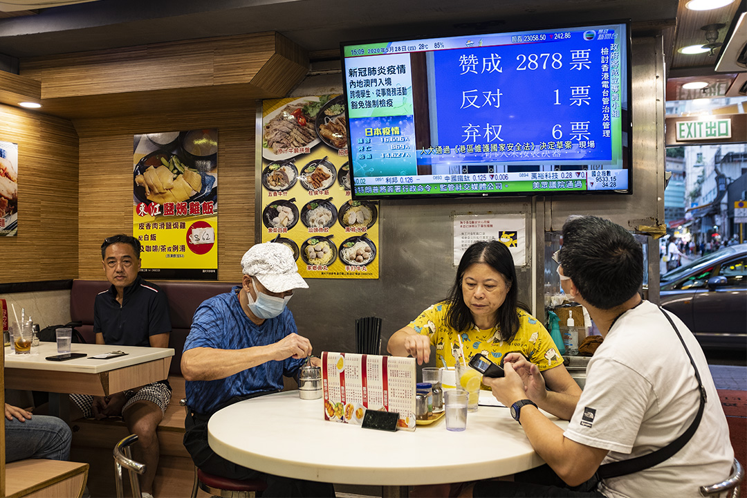 第十三届全国人大今日下午（5月28日）闭幕，以2878票赞成、1票反对、6票弃权表决通过“港区国安法”决定草案，确定将列入《基本法》附件三，由港府公布实施。 图为2020年5月28日香港茶餐厅，电视上正播放人大表决新闻。